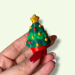 Hand holding a Christmas tree-shaped object with a star on top against a light background
