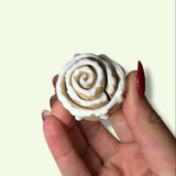 Hand holding a small white rose-shaped object against a light background