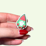 Hand holding a small colorful pin against a light background