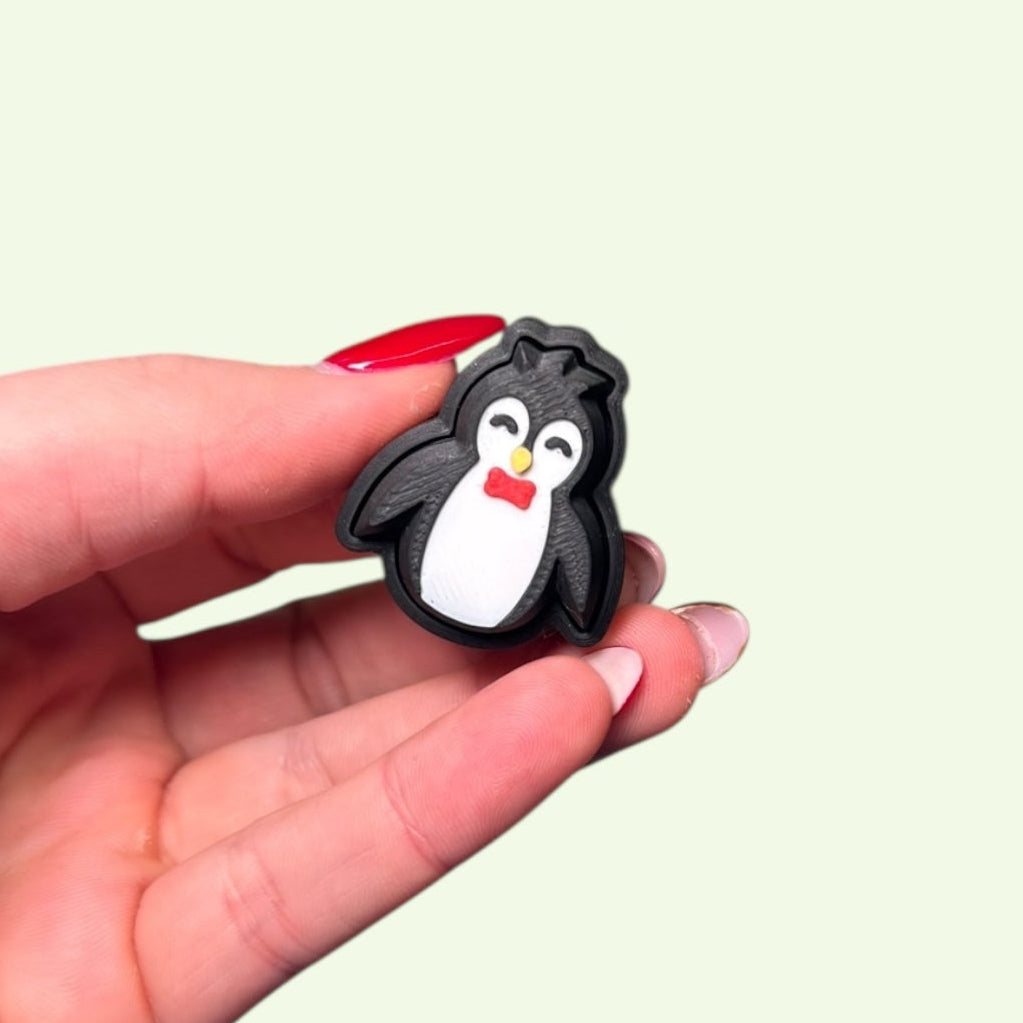 Hand holding a small penguin-shaped object against a light green background