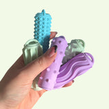 A hand holding colorful Ridglets pocket-sized sensory sticks with ridged textures for tactile therapy.