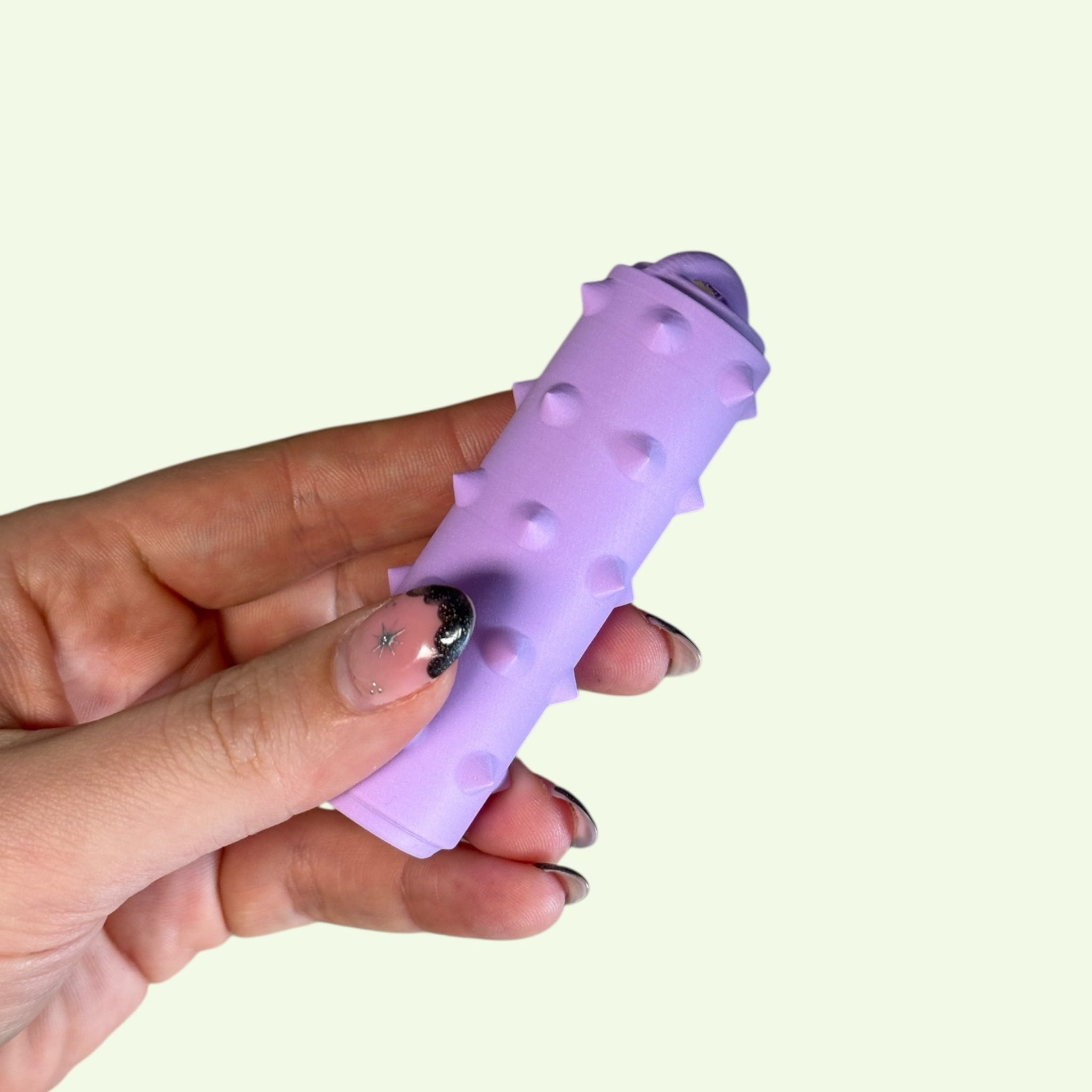 A hand holding a purple Ridglets fidget toy featuring ridged textures for sensory therapy.