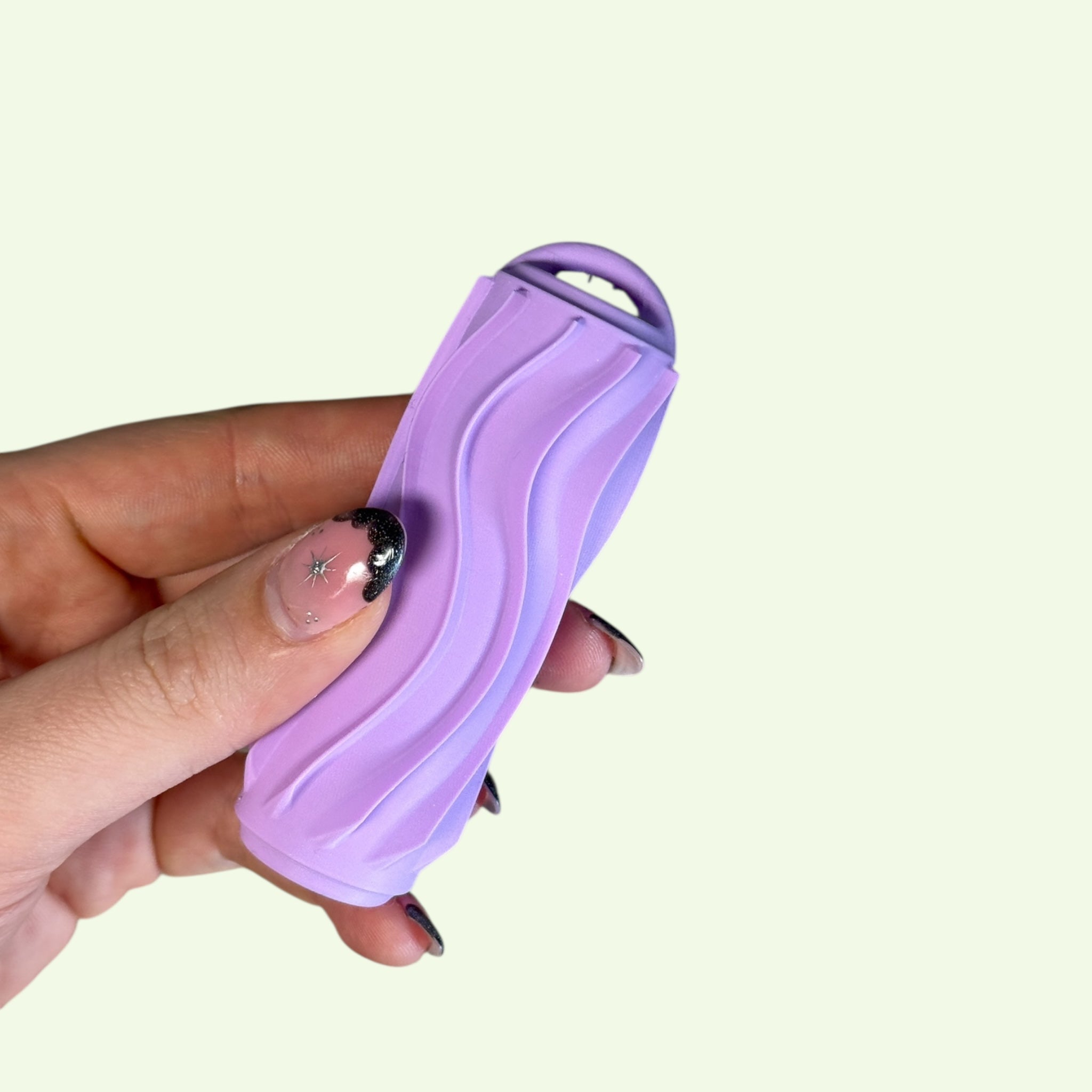 Hand holding a Ridglets pocket-sized fidget with ridged texture in purple color.