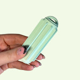 Close-up of a hand holding a Ridglets sensory stick in soft green color with ridged textures.