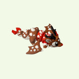 Small figurine of a character with brown fur, red accents, and white polka dots on a beige background