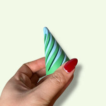 Hand holding a green and white striped cone-shaped object against a light background