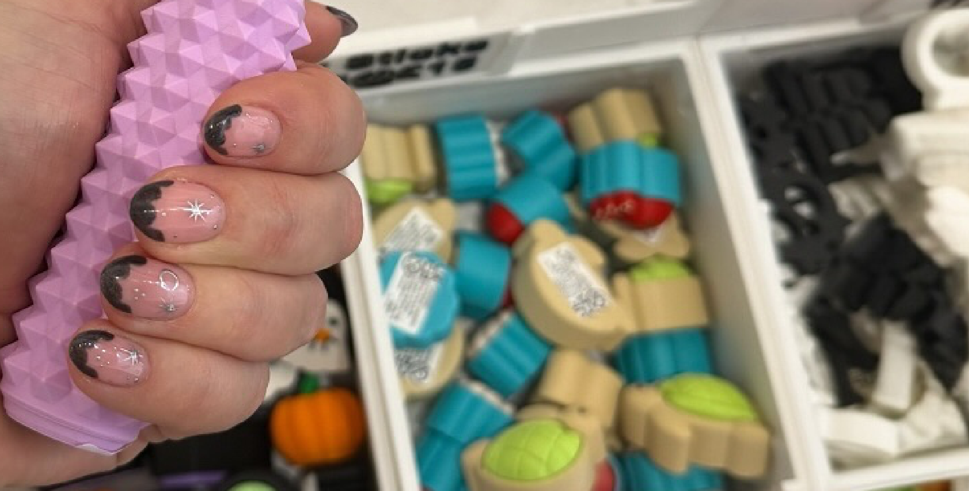 Hand holding a pink textured object with a box of colorful building blocks in the background