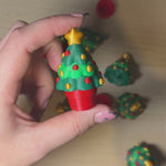 Person holding a Christmas Tree Clicker, colorful mini Christmas tree fidget toy with festive details.