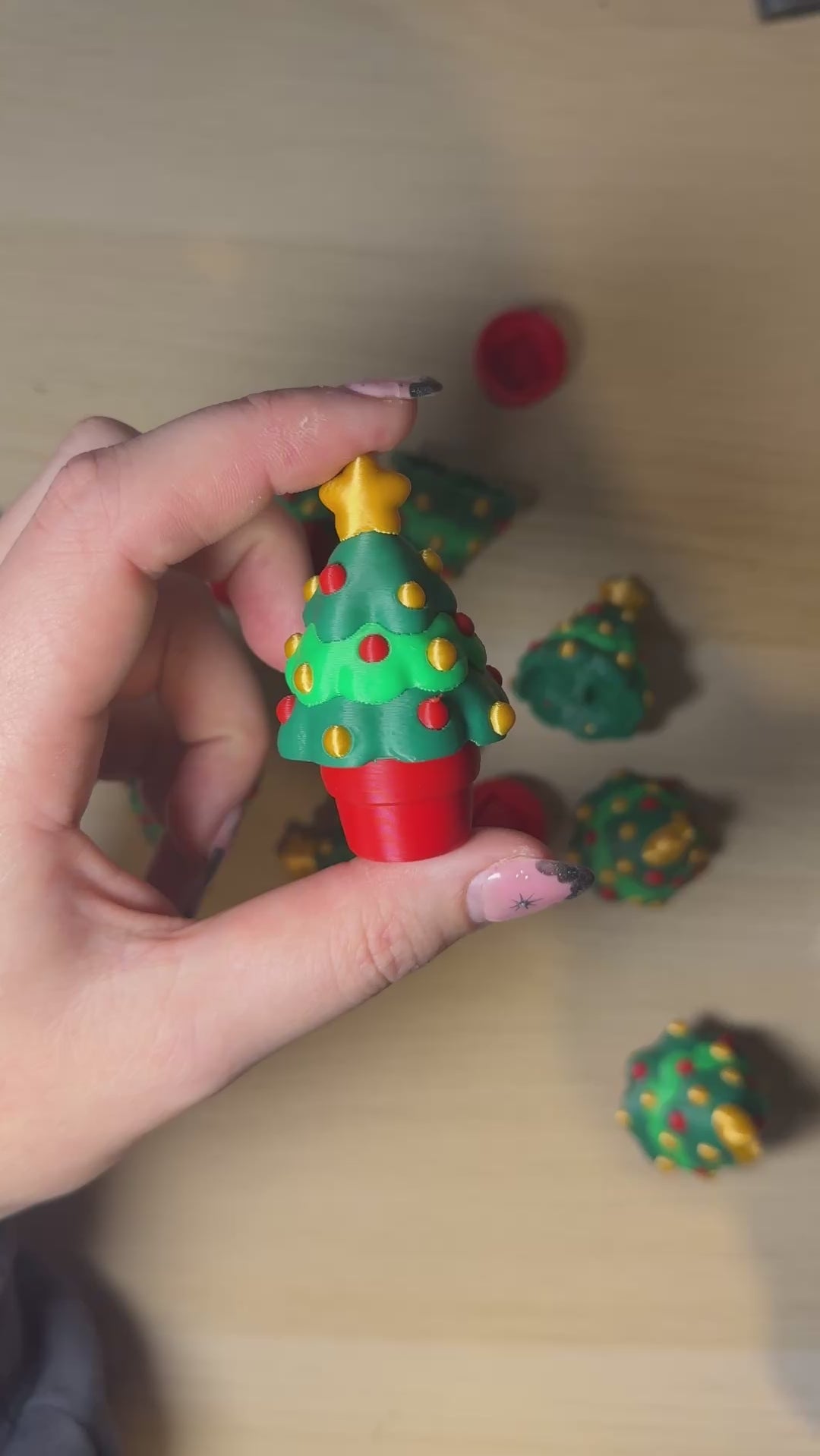 Person holding a Christmas Tree Clicker, colorful mini Christmas tree fidget toy with festive details.